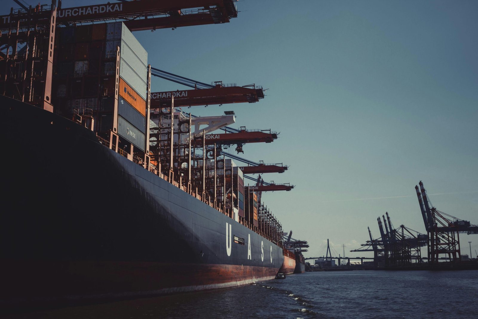 Global Shipping & Freight Management Solutions Large cargo ship loaded with containers at a port with cranes, representing international shipping and logistics operations