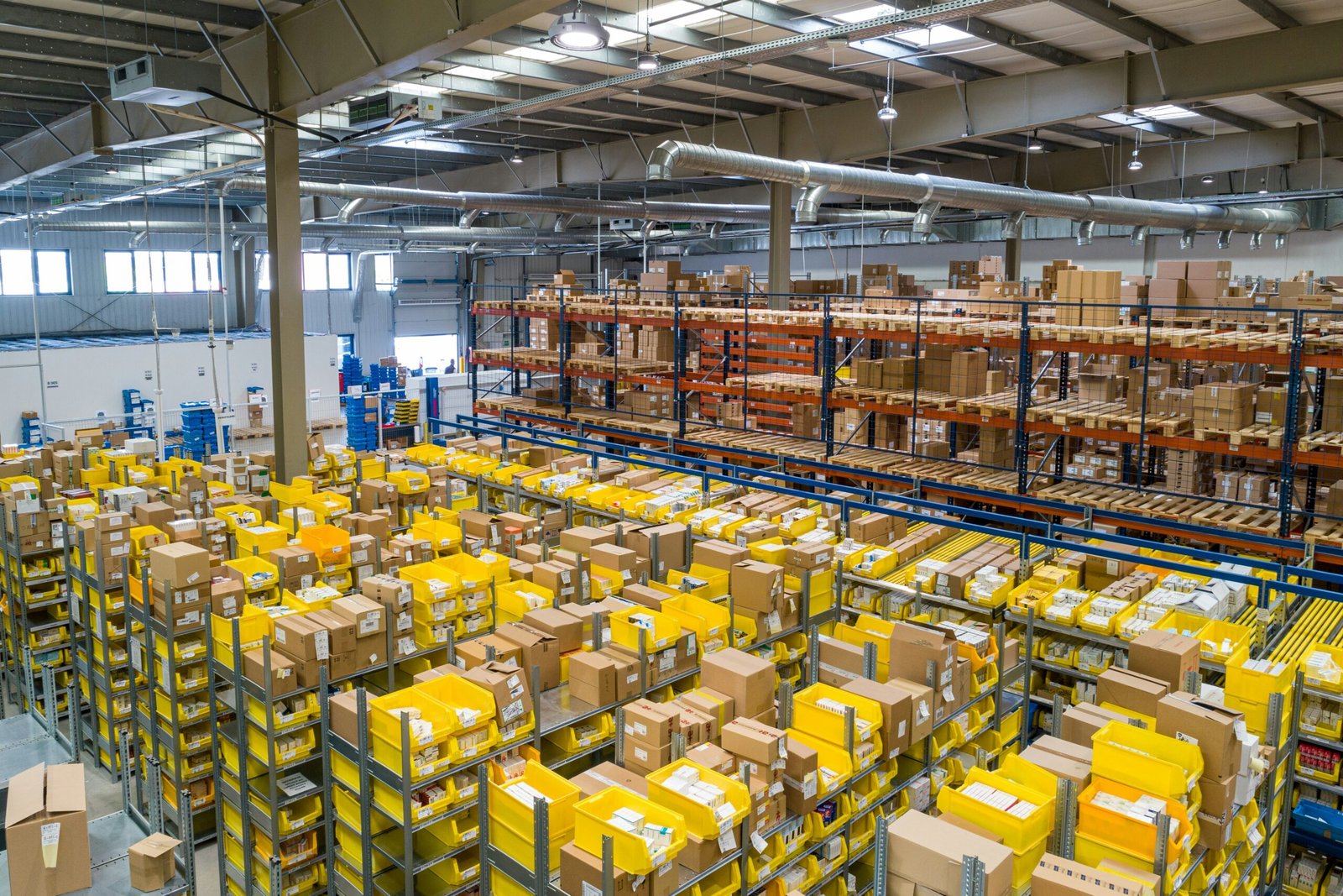 Modern Warehouse Logistics and Inventory Management Large industrial warehouse with organized shelves, stacked packages, and yellow storage bins used for logistics, inventory management, and order fulfillment.
